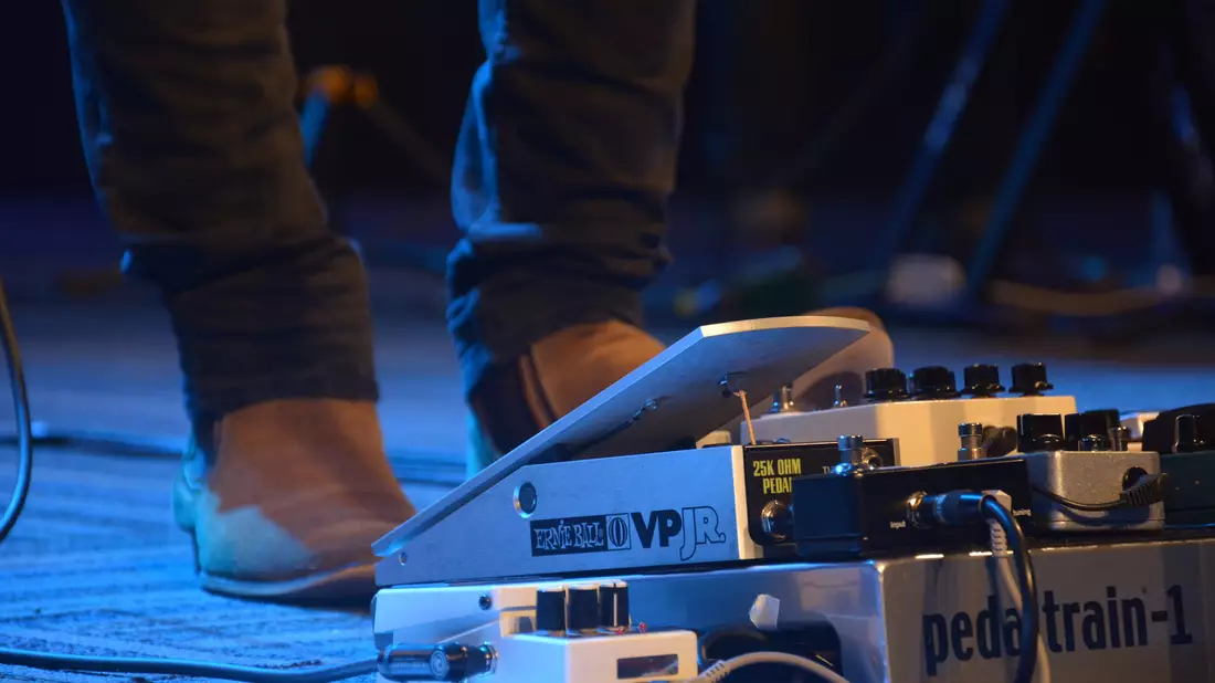 Gitarren-Effektpedale am Boden mit Fuß des Musikers am Volumenpedal auf Bühne