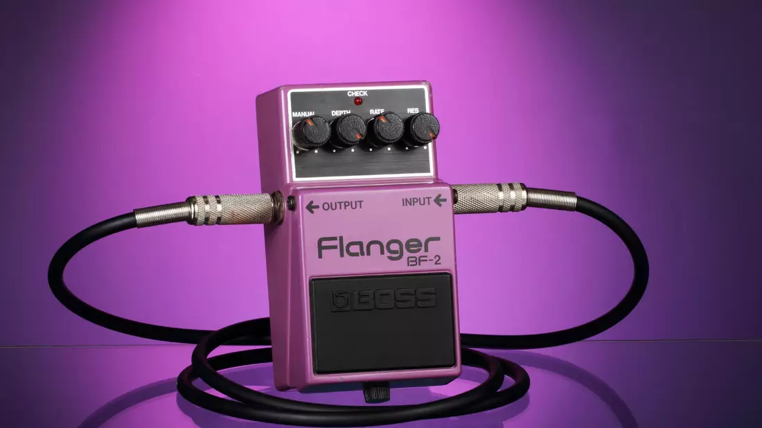 Lila Flanger-Effektpedal mit Kabeln vor violettem Hintergrund in Nahaufnahme
