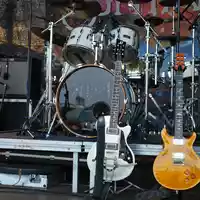 Aufgebaut für den Gig: Zwei E-Gitarren stehen bereit auf ihren Ständern, dahinter thront das Schlagzeug auf der Open-Air-Bühne. - Foto: THN