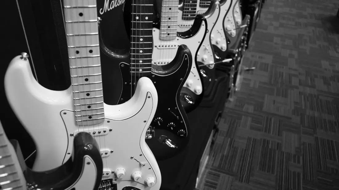 Reihe aufgereihter E-Gitarren im Musikgeschäft als Schwarzweißaufnahme