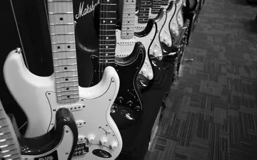 Qual der Wahl: Dicht an dicht reihen sich zahlreiche E-Gitarren auf, festgehalten in stimmungsvollem Schwarzweiß im Musikladen. - Foto: THN