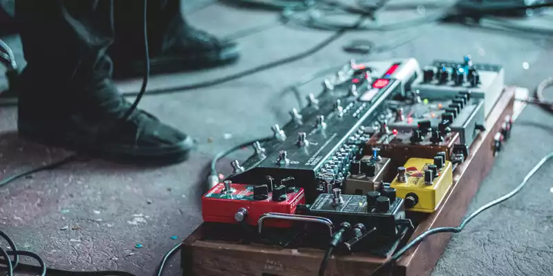 Werkzeugkasten des Sounds: Ein dicht belegtes Pedalboard mit roten, gelben und schwarzen Effektgeräten wartet am Bühnenboden. - Foto: THN