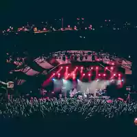 Lauschige Sommernacht: In rotes Licht getaucht spielt die Band auf der Open-Air-Bühne, während Lichter am Hang funkeln. - Foto: THN