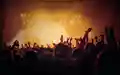 Goldene Atmosphäre: Vor einer Lichterreihe und goldgelbem Nebel verschwimmen die erhobenen Arme der Menge zu einer Silhouette. - Foto: THN