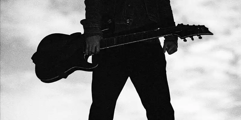 Einsame Pose im Gegenlicht: Mit der Gitarre in der Hand steht der Musiker als markante Silhouette vor dem bewölkten Himmel. - Foto: THN
