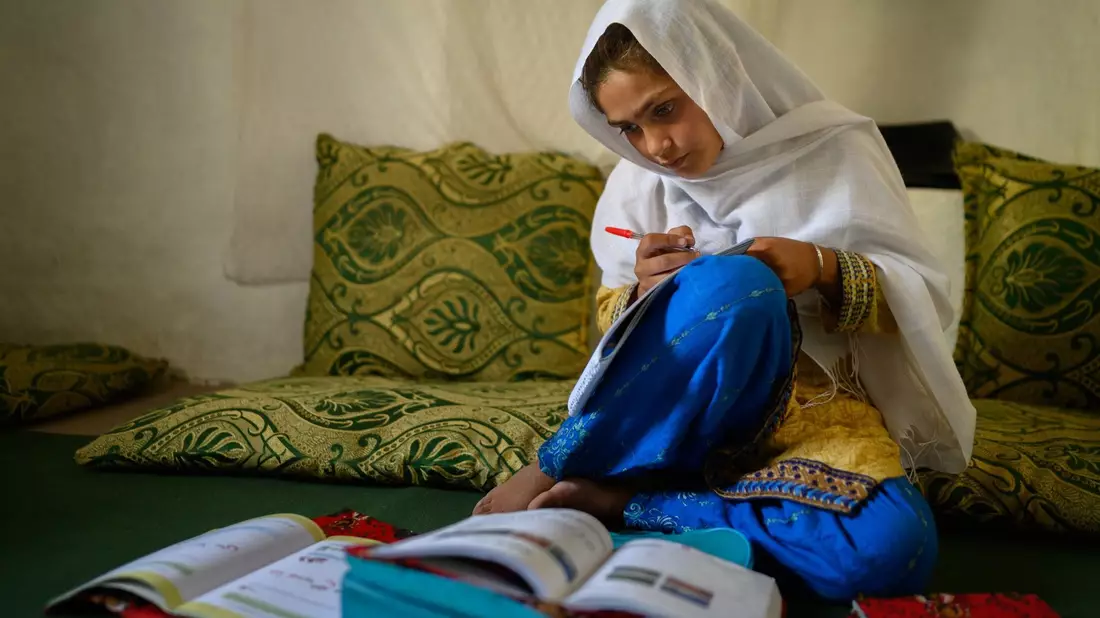 Die zehnjährige Hajira aus der afghanischen Provinz Nangarhar sitzt in einem Haus in einem abgelegenen Dorf östlich von Kabul über Schulbüchern und lernt.  - Bild: Elise Blanchard/Unicef/dpa