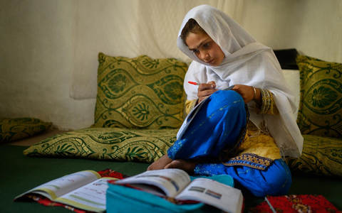 Die zehnjährige Hajira aus der afghanischen Provinz Nangarhar sitzt in einem Haus in einem abgelegenen Dorf östlich von Kabul über Schulbüchern und lernt.  - Foto: Elise Blanchard/Unicef/dpa