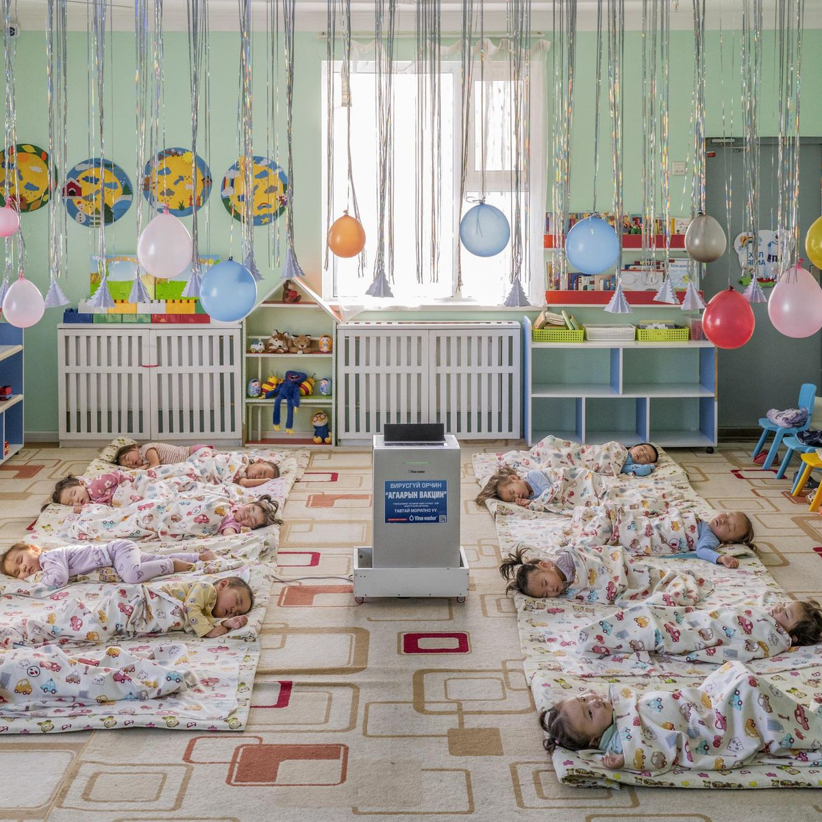 In einem Kindergarten in Ulaanbaatar, der Hauptstadt der Mongolei, liegen Kinder auf dem Boden um einen aufgestellten Luftfilter herum, der die Schadstoffkonzentration senken soll. - Foto: Natalya Saprunova/Unicef/dpa