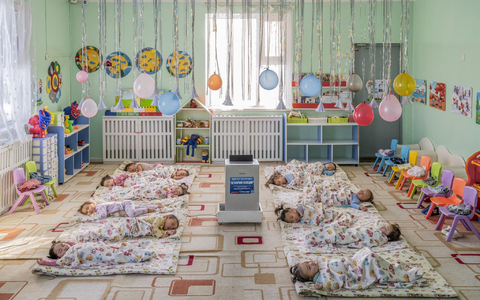 In einem Kindergarten in Ulaanbaatar, der Hauptstadt der Mongolei, liegen Kinder auf dem Boden um einen aufgestellten Luftfilter herum, der die Schadstoffkonzentration senken soll. - Foto: Natalya Saprunova/Unicef/dpa