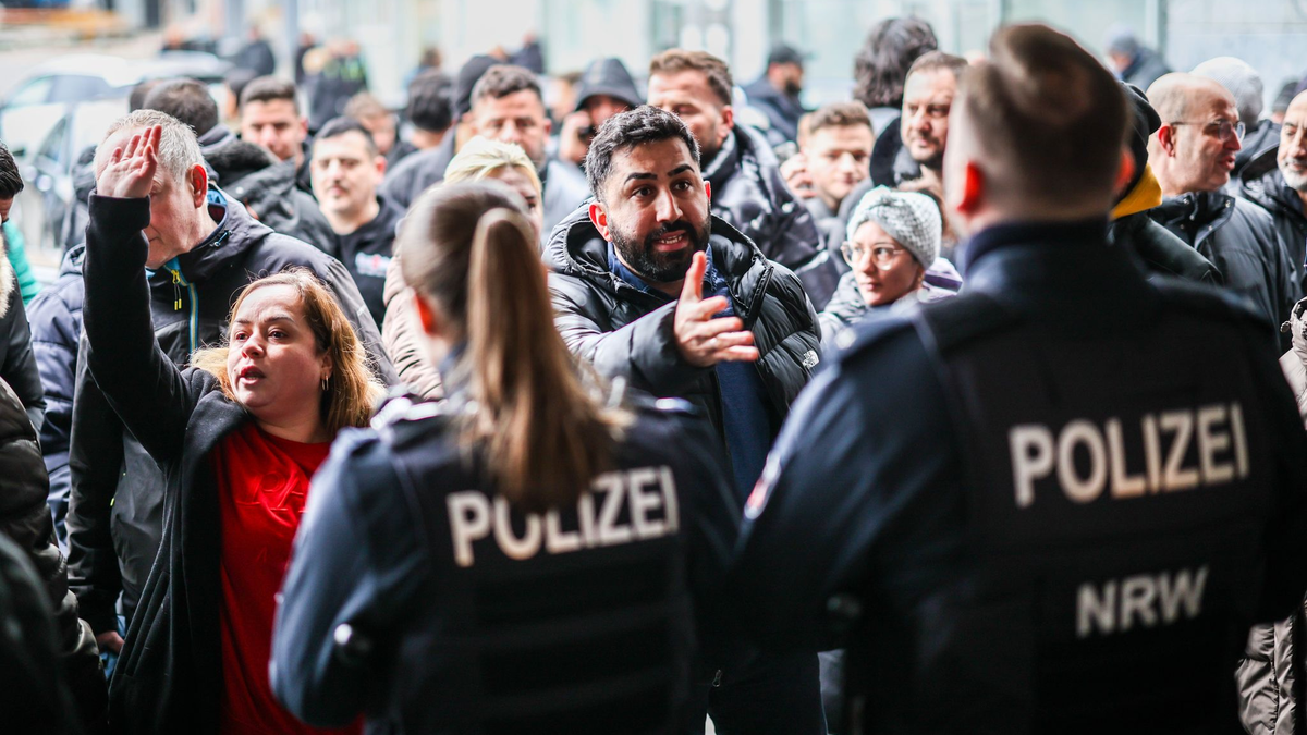 Aufgebrachte Kunden diskutieren vor der Sparkassenfiliale mit Polizeibeamten (Archivfoto) - Foto: Christoph Reichwein/dpa