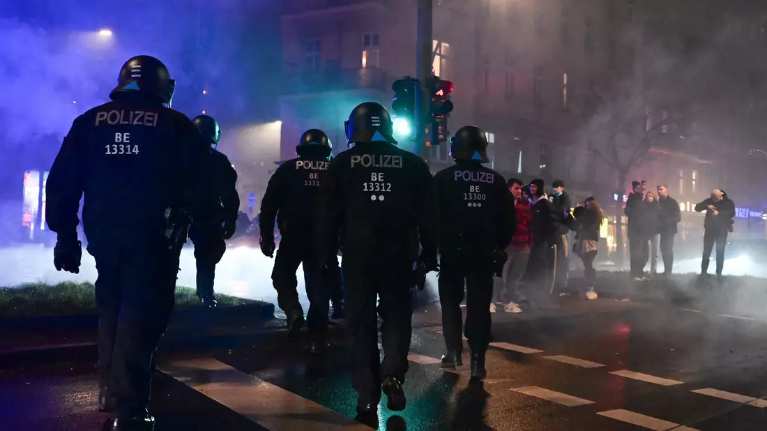 Feuerwerk brennt während der Silvesternacht in Neukölln vor einem Polizeiauto. - Bild: Sebastian Christoph Gollnow/dpa