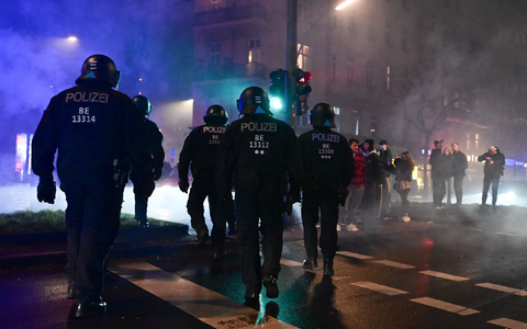 Feuerwerk brennt während der Silvesternacht in Neukölln vor einem Polizeiauto. - Foto: Sebastian Christoph Gollnow/dpa