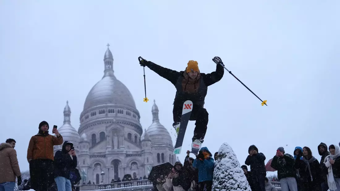 Ein Mann springt mit seinen Skiern den Hügel bei der Basilika Sacre-Coeur im französischen Paris hinunter. - Bild: Aurelien Morissard/AP/dpa
