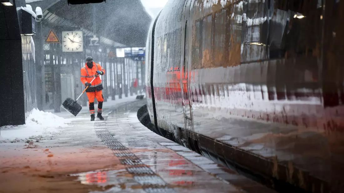 Mitarbeiter schieben Schnee von einem Bahnsteig am Hamburger Hauptbahnhof. - Bild: Christian Charisius/dpa
