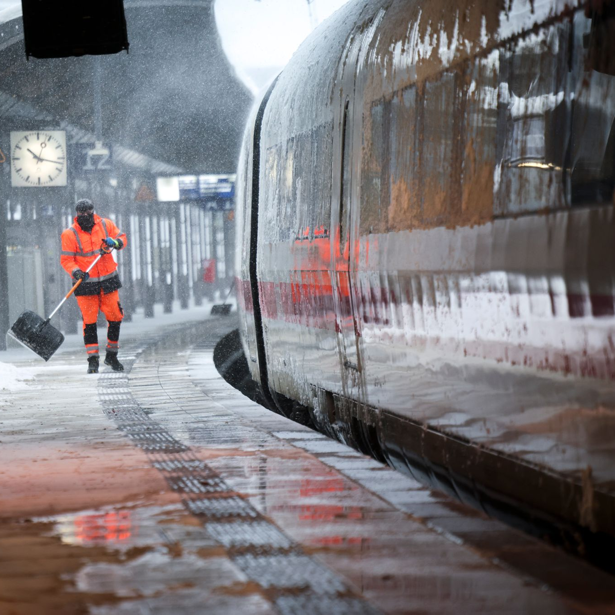 Mitarbeiter schieben Schnee von einem Bahnsteig am Hamburger Hauptbahnhof. - Foto: Christian Charisius/dpa