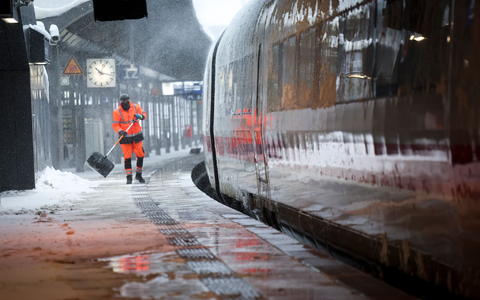 Mitarbeiter schieben Schnee von einem Bahnsteig am Hamburger Hauptbahnhof. - Foto: Christian Charisius/dpa