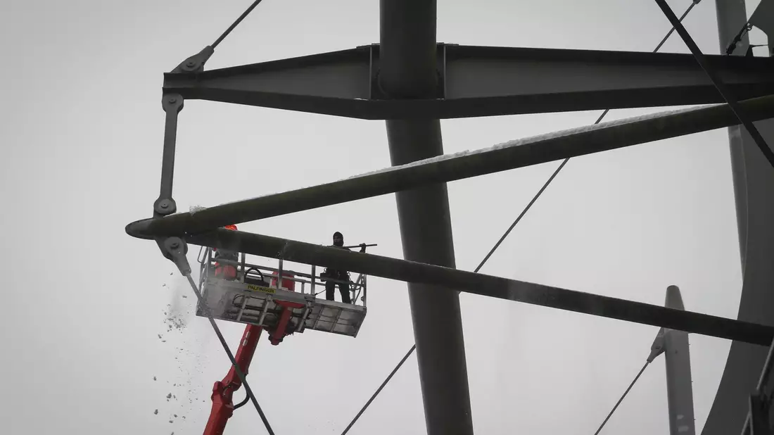 Arbeiter mit einem Hubsteiger entfernen Eis und Schnee von den Trägern des Stadiondachs in Hamburg. - Bild: Christian Charisius/dpa