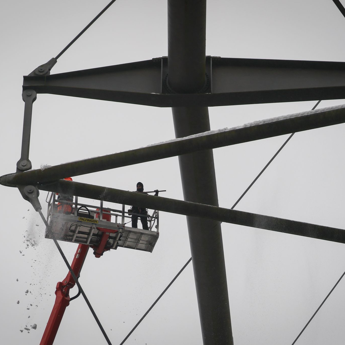 Arbeiter mit einem Hubsteiger entfernen Eis und Schnee von den Trägern des Stadiondachs in Hamburg. - Foto: Christian Charisius/dpa