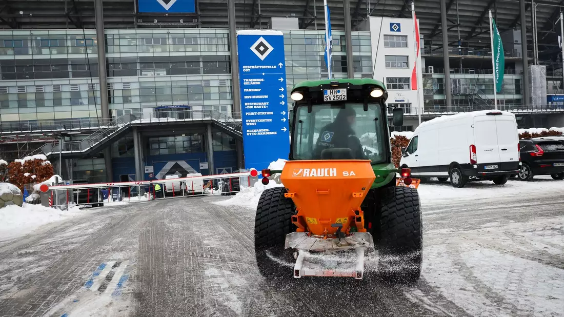 Ein kleines Räum- und Streufahrzeug ist auf dem Parkplatz am Volksparkstadion unterwegs. - Bild: Christian Charisius/dpa