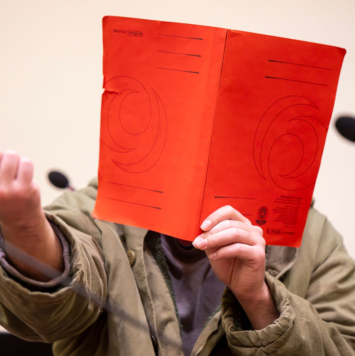 Der Angeklagte verdeckte sein Gesicht zum Prozessauftakt zunächst mit einer Mappe. - Foto: Peter Kneffel/dpa