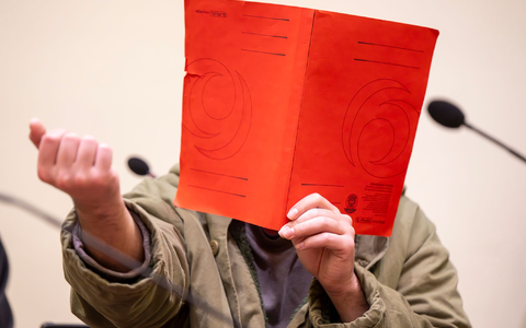 Der Angeklagte verdeckte sein Gesicht zum Prozessauftakt zunächst mit einer Mappe. - Foto: Peter Kneffel/dpa