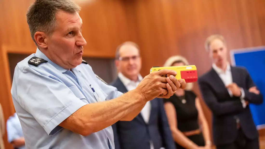 Ein Polizist erklärte die Funktionsweise eines Distanz-Elektroimpulsgeräts im vergangenen Jahr im Innnenministerium. (Archivfoto) - Bild: Michael Kappeler/dpa