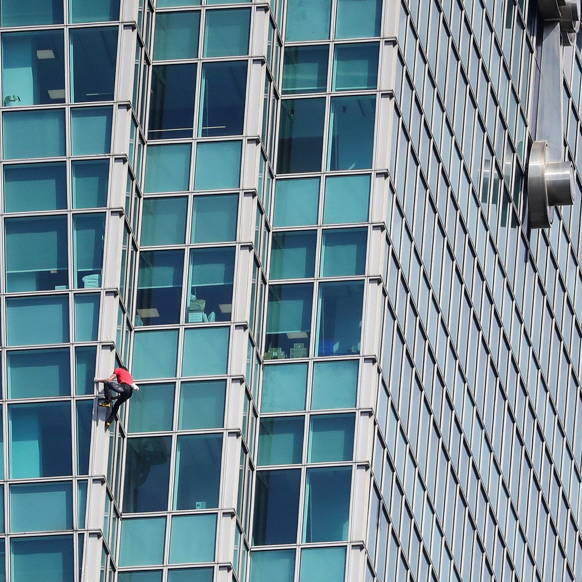Schaulustige beobachteten Alex Honnold nicht nur vom Boden aus - auch hinter den Bürofenstern wurde der Extremsportler angefeuert. - Foto: ChiangYing-ying/AP/dpa