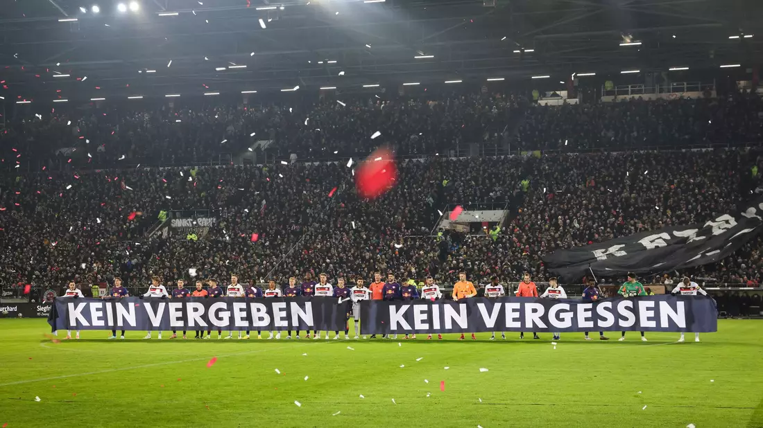 Spieler beider Teams halten vor Spielbeginn ein Banner anlässlich das Holocaust-Gedenktags hoch. - Bild: Christian Charisius/dpa