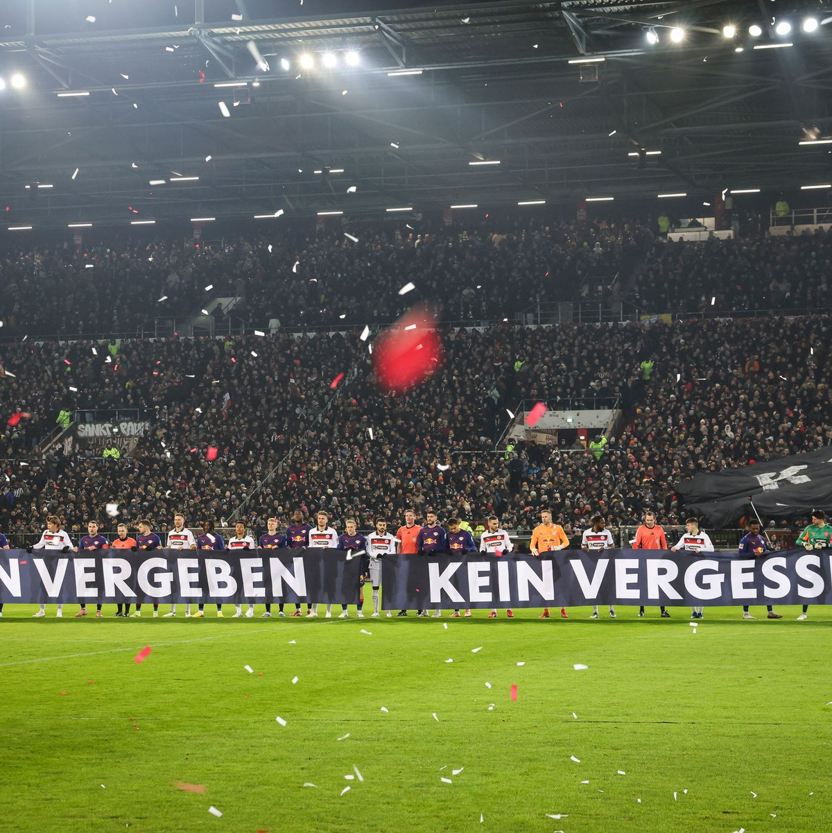 Spieler beider Teams halten vor Spielbeginn ein Banner anlässlich das Holocaust-Gedenktags hoch. - Foto: Christian Charisius/dpa