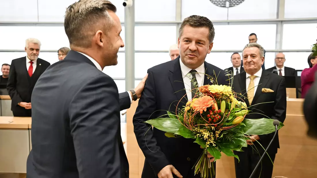 Sven Schulze bekommt Glückwünsche und einen Blumenstrauß vom AfD-Spitzenkandidaten Ulrich Siegmund.  - Bild: Hendrik Schmidt/dpa