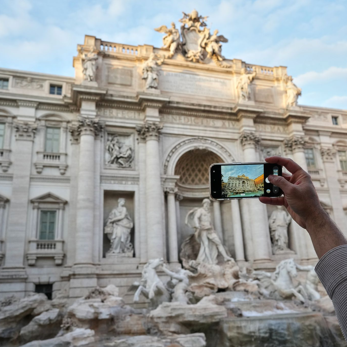 Ein Besucher macht ein Foto des Trevi-Brunnens. (Archivbild) - Foto: Andrew Medichini/AP/dpa