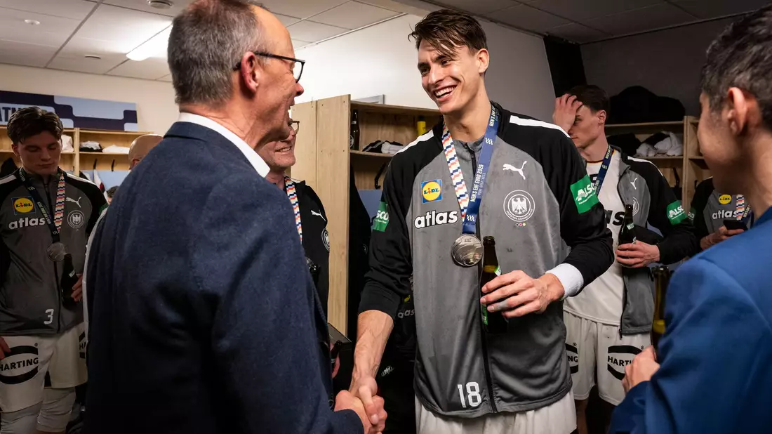 Bundeskanzler Friedrich Merz gratuliert Deutschlands Handballern in der Kabine.  - Bild: Guido Bergmann/Presse- und Informationsamt der Bundesregierung/dpa