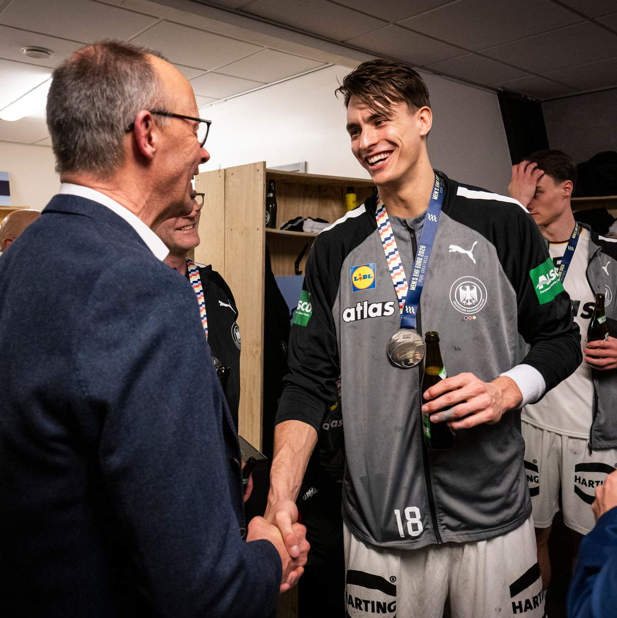 Bundeskanzler Friedrich Merz gratuliert Deutschlands Handballern in der Kabine.  - Foto: Guido Bergmann/Presse- und Informationsamt der Bundesregierung/dpa