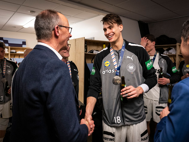 Bundeskanzler Friedrich Merz gratuliert Deutschlands Handballern in der Kabine.  - Foto: Guido Bergmann/Presse- und Informationsamt der Bundesregierung/dpa