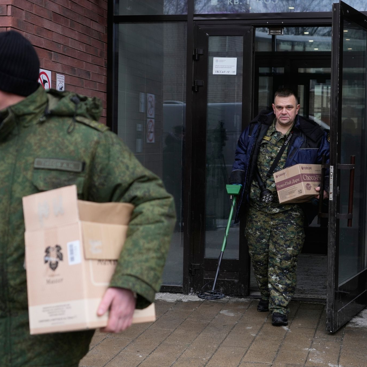 Ermittler verlassen das Gebäude, in dem die Schüsse auf den General abgefeuert wurden - er selbst liegt im Krankenhaus. - Foto: Pavel Bednyakov/AP/dpa