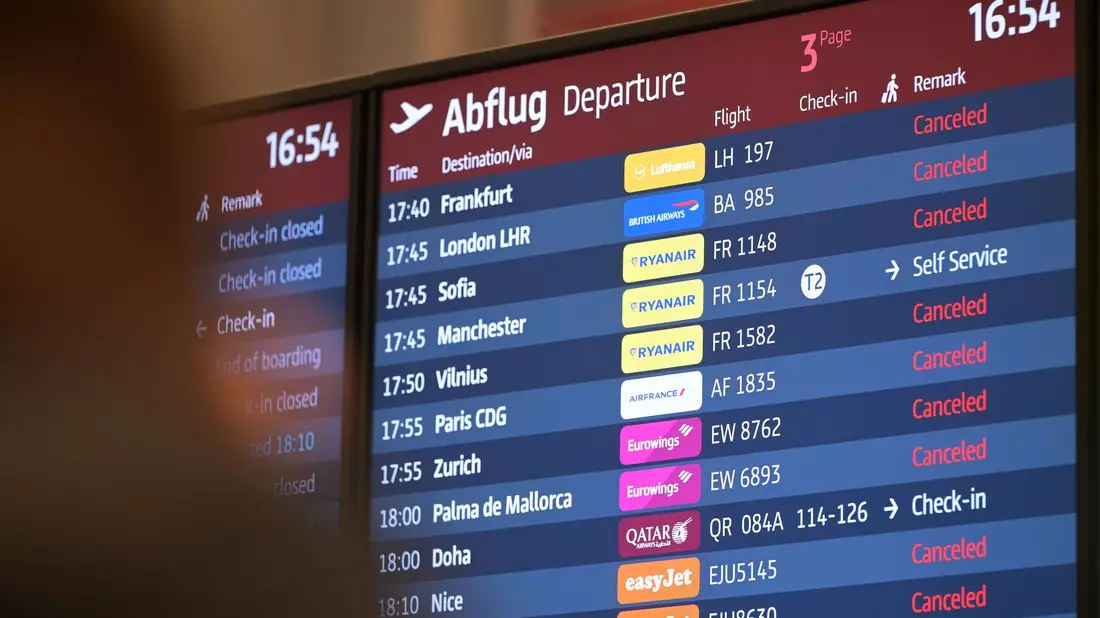 Passagiere blicken auf eine Anzeigetafel am Hauptstadtflughafen BER. - Bild: Michael Bahlo/dpa