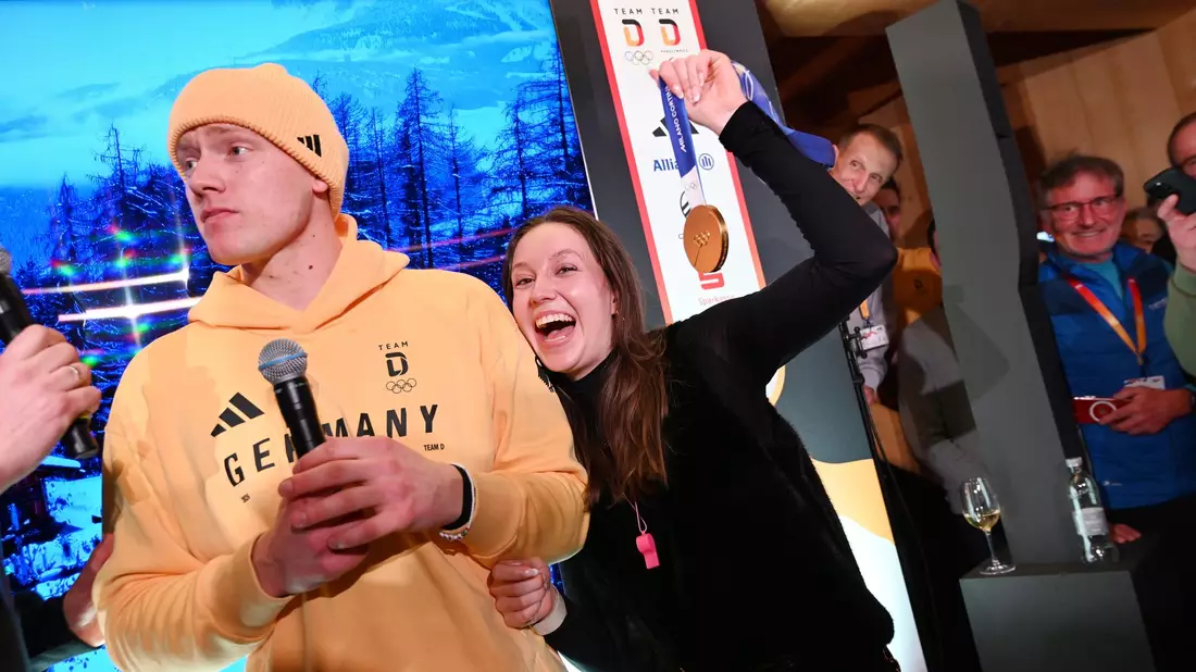 Rodler Max Langenhan steht mit seiner Freundin Susi auf der Bühne und singt das Thüringenlied mit seinen Fans. - Bild: Frank May/ picture alliance/Team D/dpa