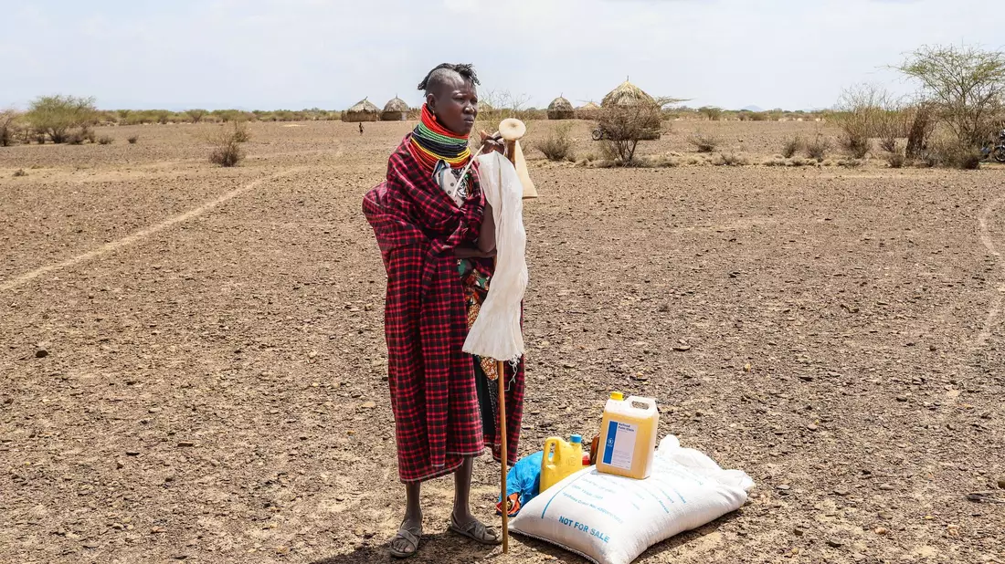 Eine Frau steht in Kenia neben einer Lebensmittelration des Welternährungsprogramms (WFP). - Bild: Patrick Ngugi/AP/dpa