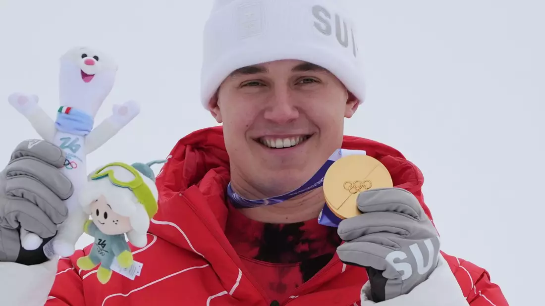 Franjo von Allmen zeigt eine seiner drei olympischen Goldmedaillen. - Bild: Rebecca Blackwell/AP/dpa