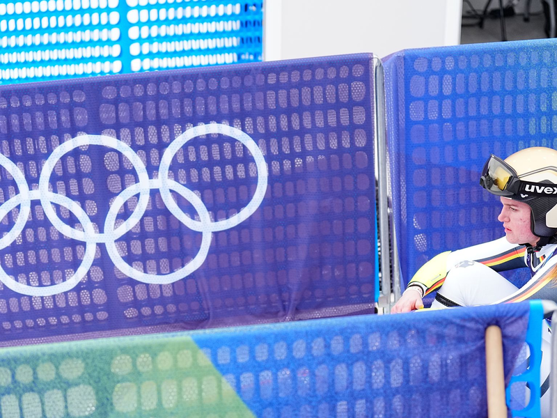 Emma Aicher sitzt nach ihrem Aus im Super-G frustriert im Zielbereich von Cortina d'Ampezzo. - Foto: Michael Kappeler/dpa