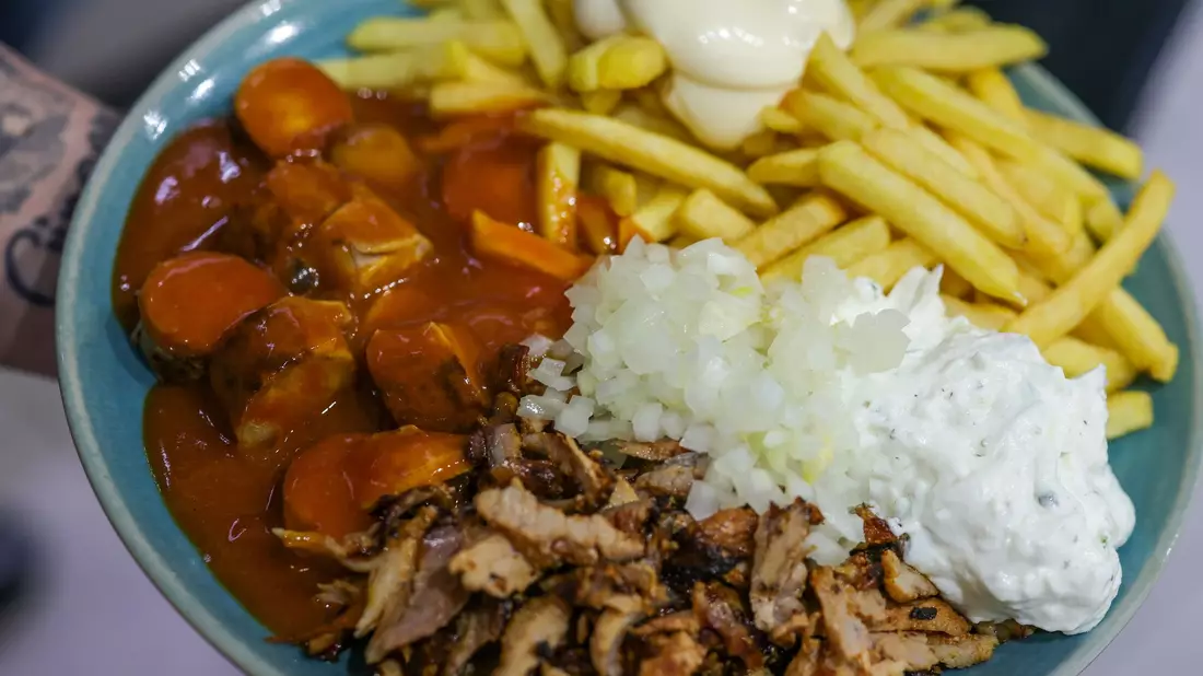 Imbiss mit Gehalt: Currywurst (links), Pommes frites mit Mayonnaise (oben) und Gyrosfleisch mit Zwiebeln und Tzatziki. - Bild: Christoph Reichwein/dpa