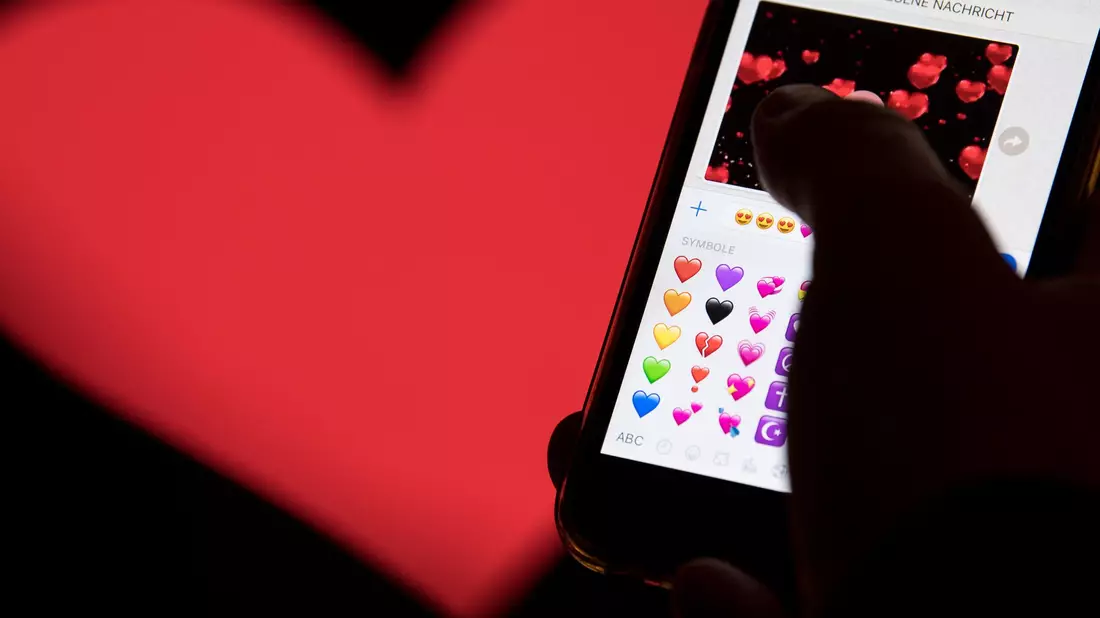Hand aufs Handy - das rote Herz zählt zu den beliebtesten Emojis. (Archivbild) - Bild: Fabian Sommer/dpa
