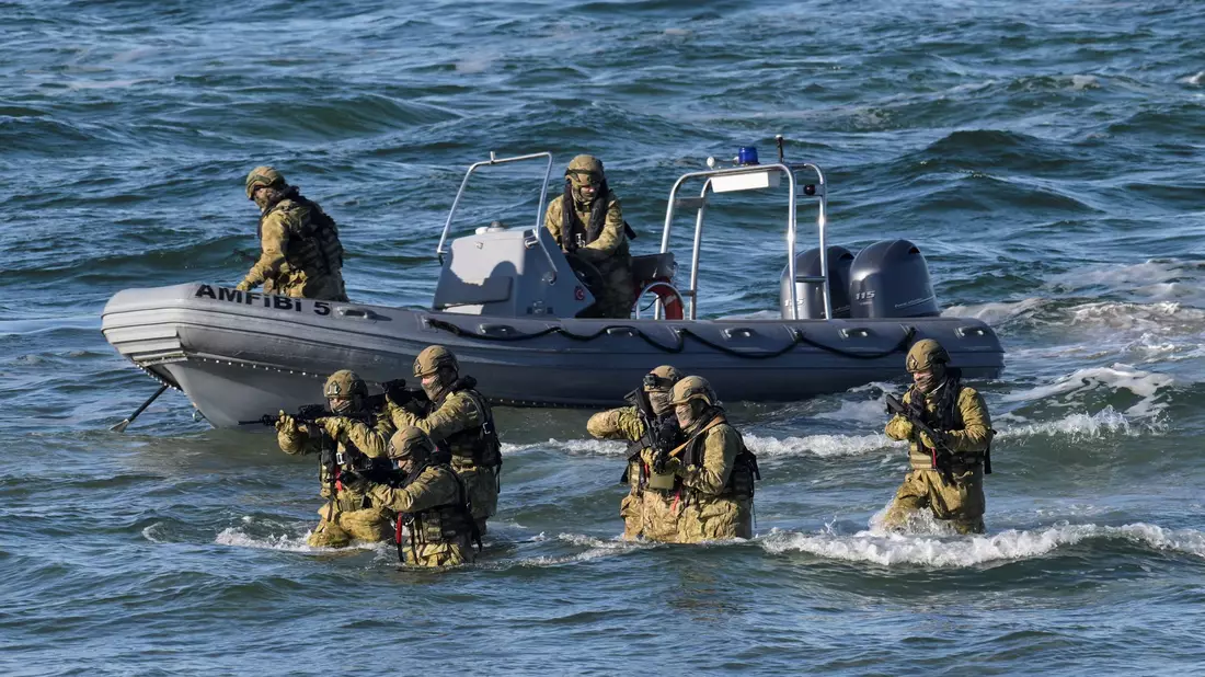 Taucher machen den Anfang und steigen aus dem Wasser auf den schneebedeckten Strand, um den Küstenabschnitt zu sichern. - Bild: Fabian Bimmer/Reuters/Pool/dpa