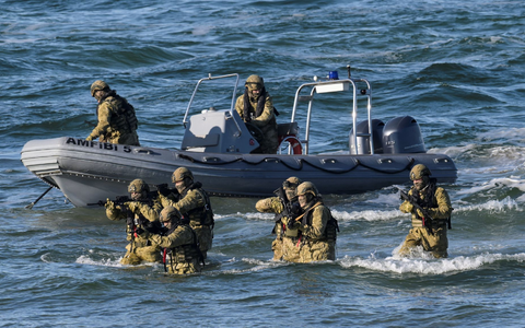 Taucher machen den Anfang und steigen aus dem Wasser auf den schneebedeckten Strand, um den Küstenabschnitt zu sichern. - Foto: Fabian Bimmer/Reuters/Pool/dpa
