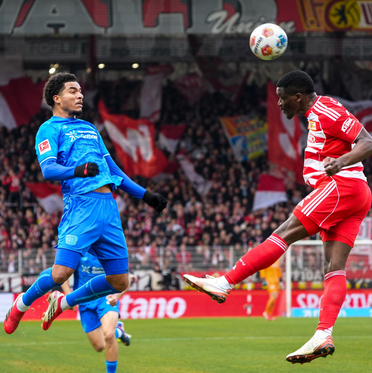 Union Berlins Nsoki (r.) setzt sich im Kopfballduell mit Leverkusens Tillmann (l.) durch.  - Foto: Soeren Stache/dpa