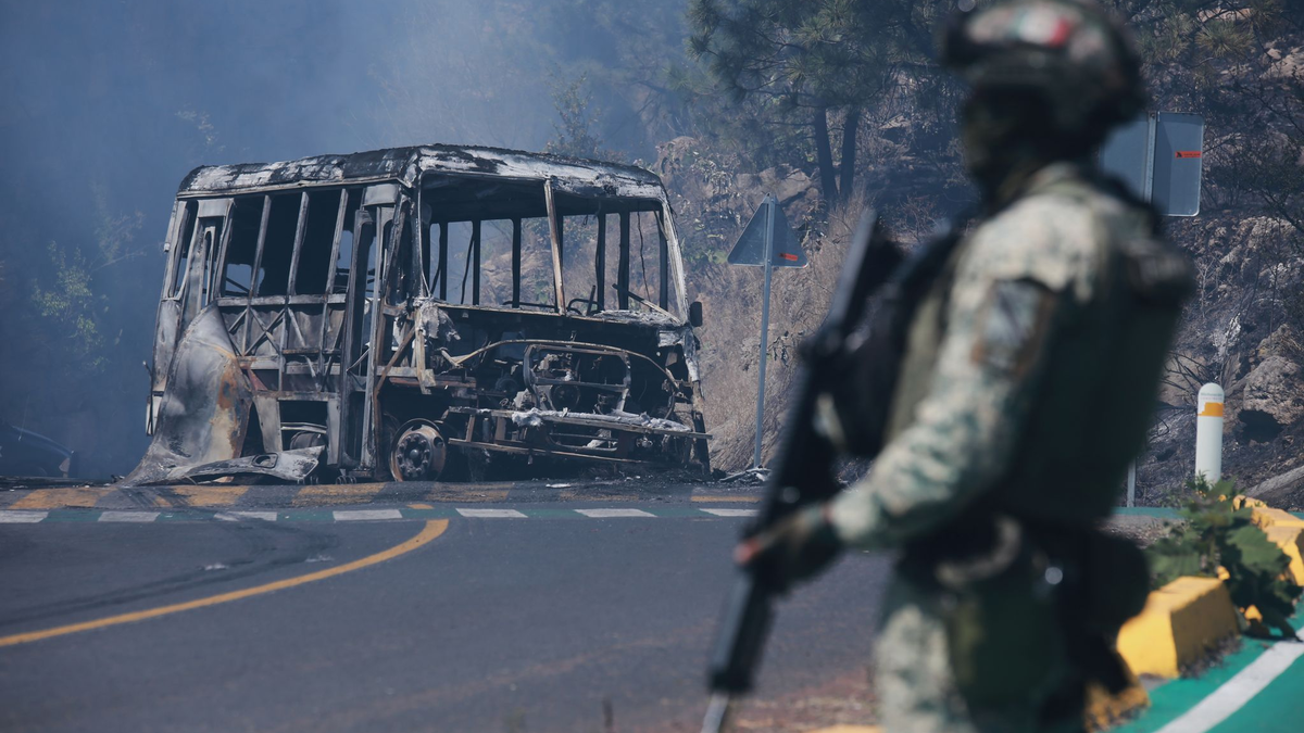 Ein Soldat steht in Mexiko - einem der drei Ausrichterländer der Fußball-WM im Sommer - neben einem ausgebrannten Bus. - Foto: Armando Solis/AP/dpa