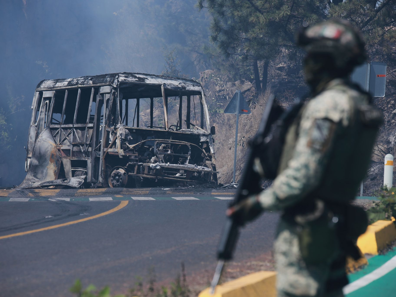 Ein Soldat steht in Mexiko - einem der drei Ausrichterländer der Fußball-WM im Sommer - neben einem ausgebrannten Bus. - Foto: Armando Solis/AP/dpa