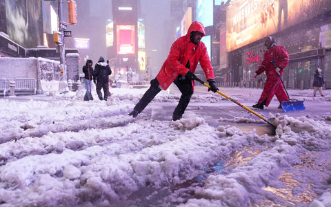 Ein Arbeiter schaufelt Schnee auf dem Times Square in New York. Ein heftiger Schneesturm zieht über den Nordosten der USA hinweg. - Foto: Seth Wenig/AP/dpa
