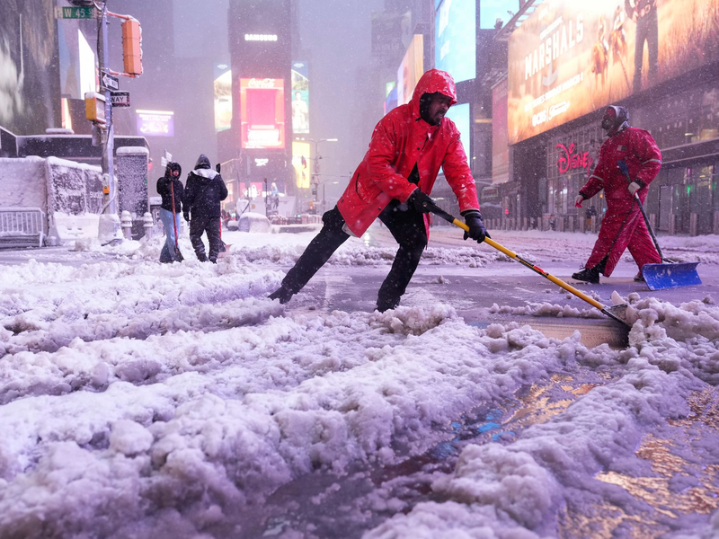 Ein Arbeiter schaufelt Schnee auf dem Times Square in New York. Ein heftiger Schneesturm zieht über den Nordosten der USA hinweg. - Foto: Seth Wenig/AP/dpa