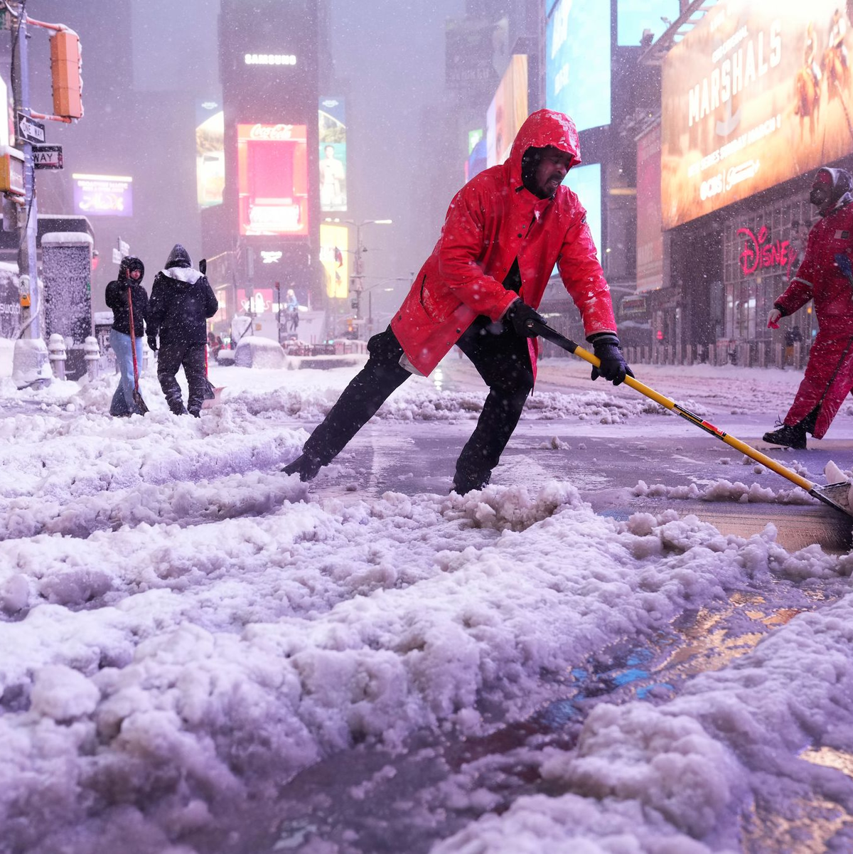 Ein Arbeiter schaufelt Schnee auf dem Times Square in New York. Ein heftiger Schneesturm zieht über den Nordosten der USA hinweg. - Foto: Seth Wenig/AP/dpa